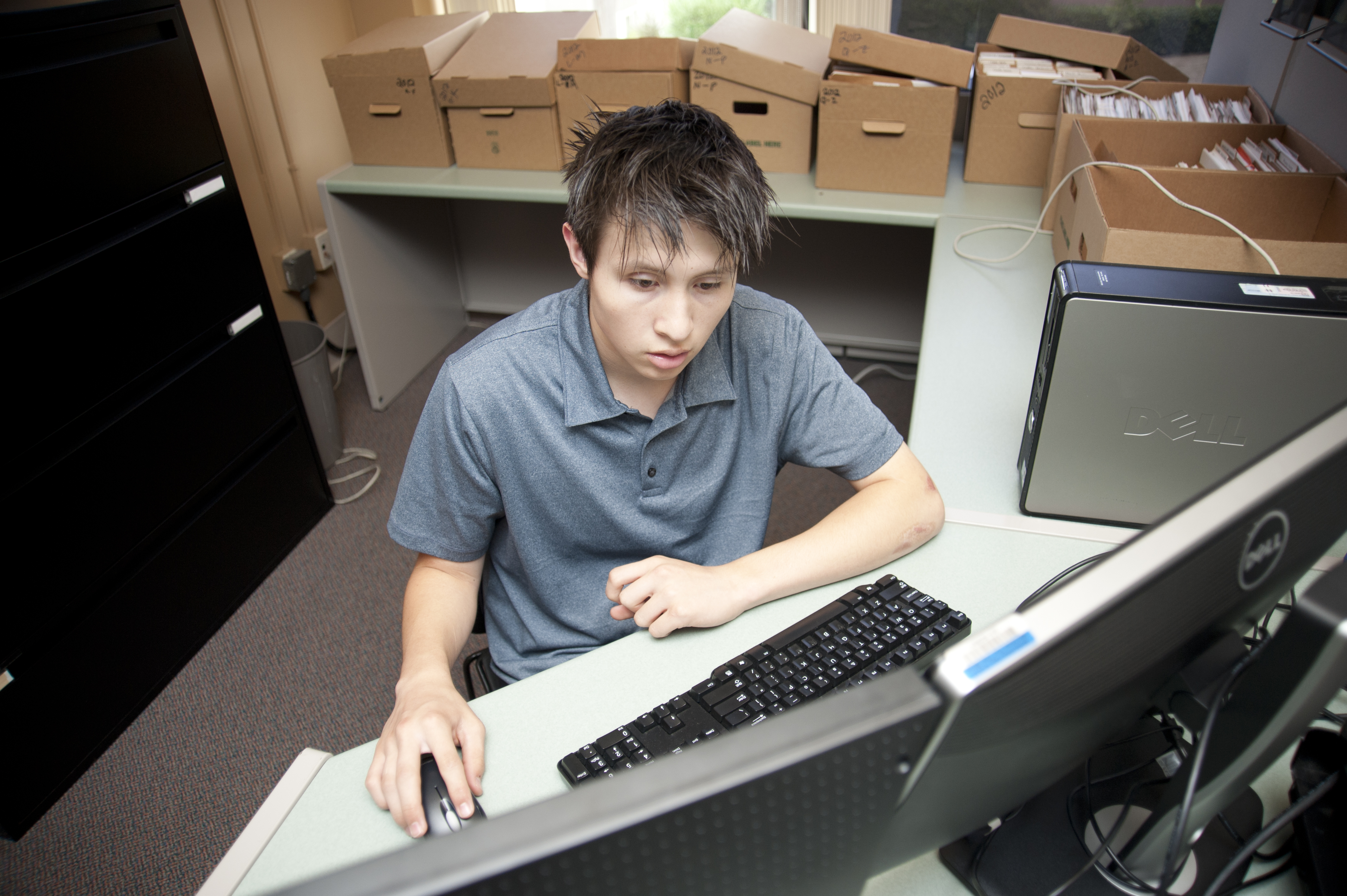 A young man working on a computer in a small office.