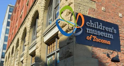 Exterior of Tacoma Children's Museum showing the museum logo on a red brick wall.