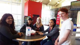 Several Bridge students gather around a table in the Eastern Washington University Student Cafeteria.