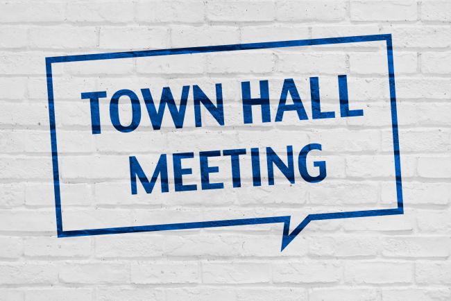 A chat bubble that says “Town Hall Meeting” stenciled on a white brick wall.
