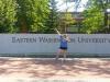 A young woman strikes a pose in front of a long wall with “Eastern Washington University” carved in its surface.