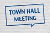 A chat bubble that says “Town Hall Meeting” stenciled on a white brick wall.